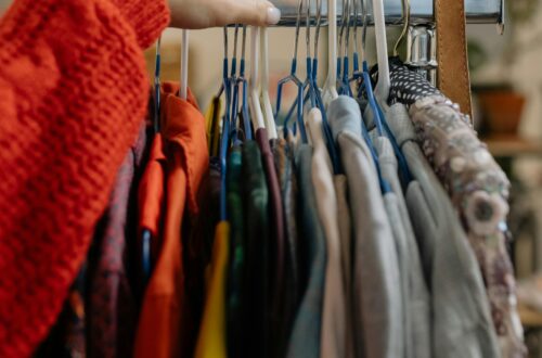 A woman browsing garments on hangers in a retail clothing store.